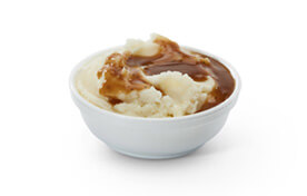 A bowl of mashed potatoes and gravy.